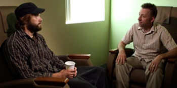 Image of two caucasian men sitting together and talking.