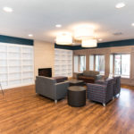 Image of the Sanderson Apartment Library. There are empty white shelves and four couches with side tables.
