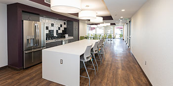 The community room at Sanderson Apartments. The image features a white quartz counter, bar stools, and a large refrigerator.