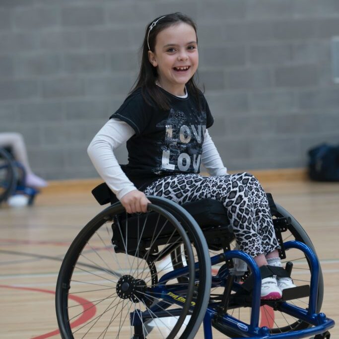 little girl in sport wheelchair in school gym