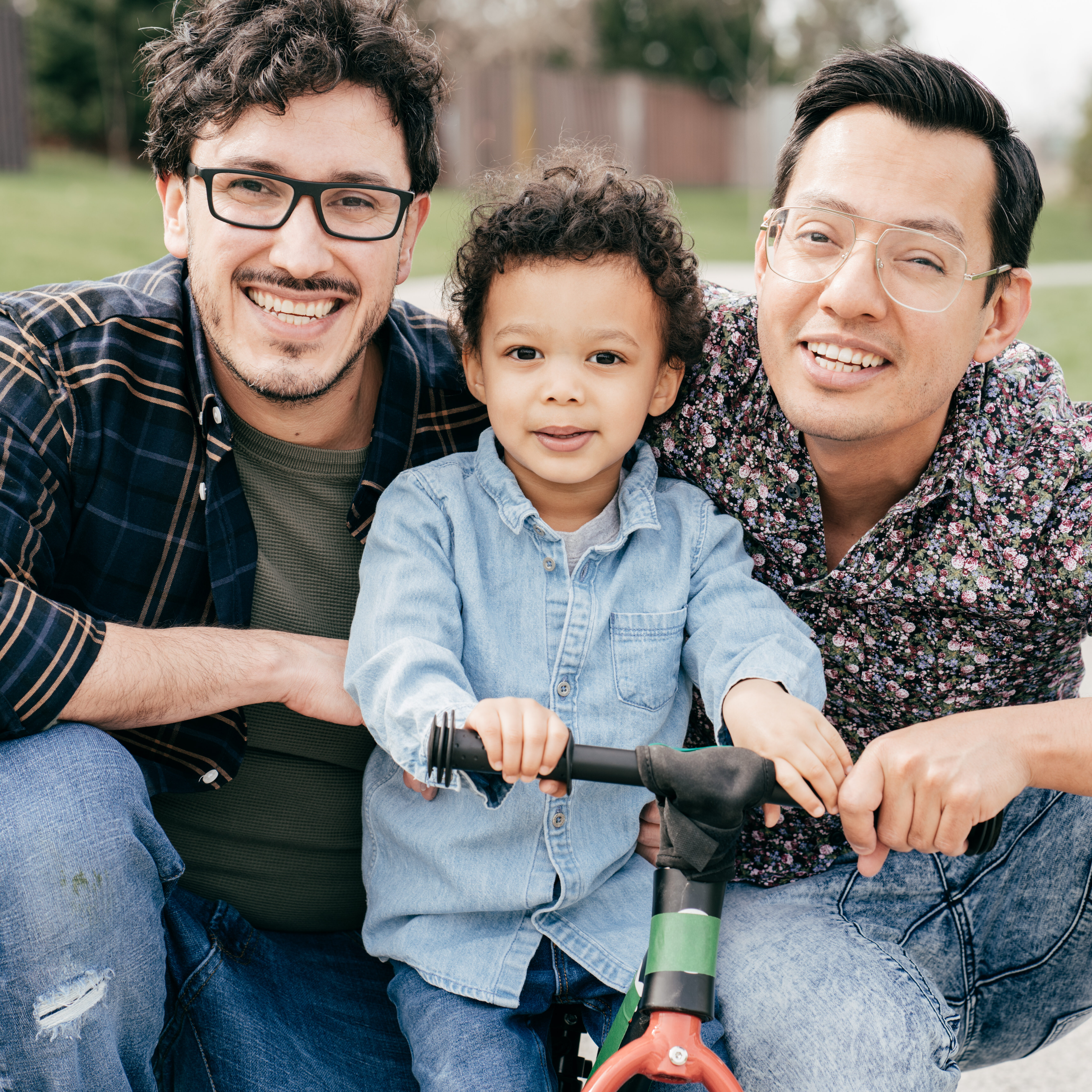 Two dads with toddler son having fun outdoor