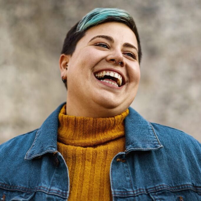 A,Young,Woman,Of,Non-binary,Sexuality,Smiles,Showing,Her,Teeth